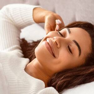 Happy young African American woman stretching arms while waking up.