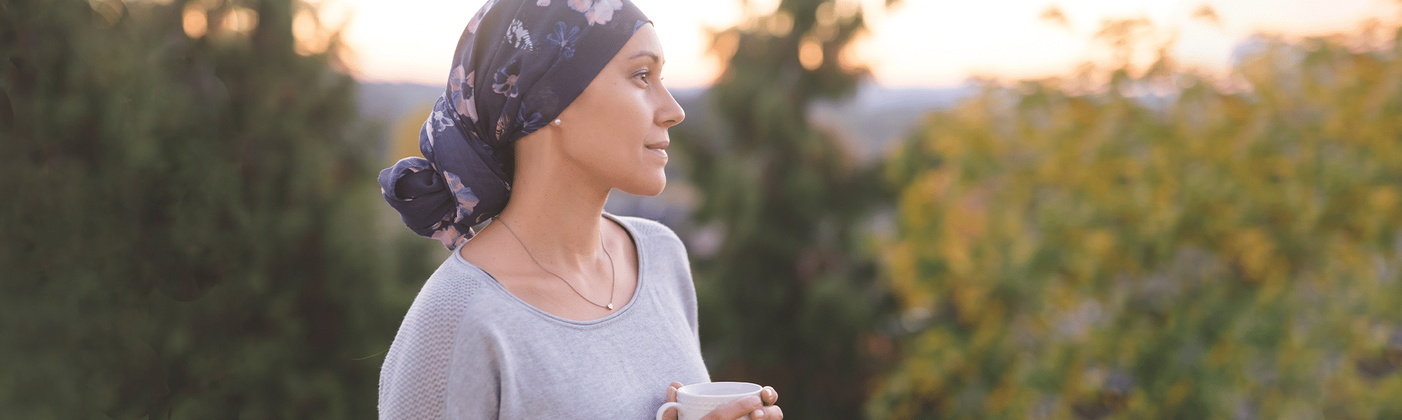 Woman wearing a head wrap looks off in the distance while standing outside