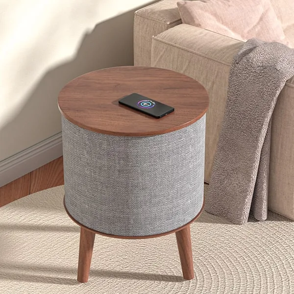 Scene-Graph-for-Drum-Shape-Speaker-4-min Sonic Side Table in Walnut with a phone charging on its top, next to a sofa.